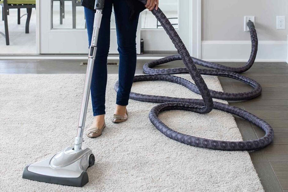 Woman using central vacuum system in home.